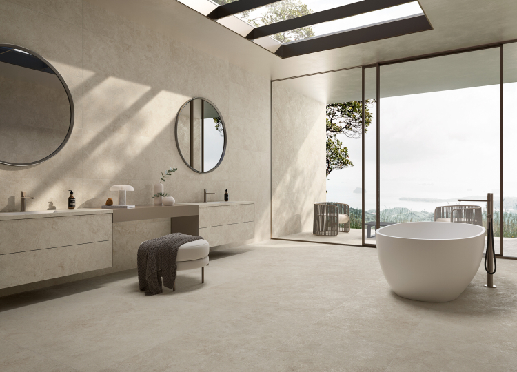 Badezimmer mit Blick nach Draußen, freistehender Badewanne und Waschtisch, am Boden und auf der Wand schlichte Fliesen in derselben Optik