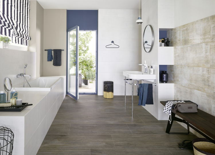 Badezimmer mit weißen Badezimmermöbeln und blauen Farb-Elementen auf dunklen Großformat-Fliesen.