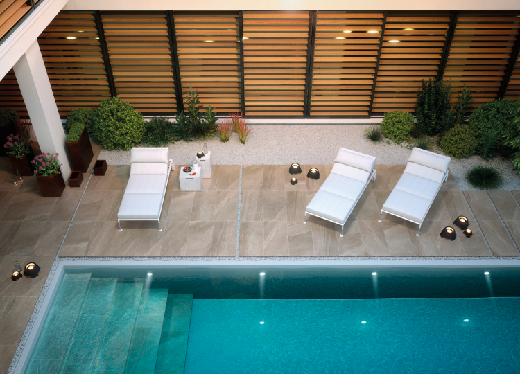 Moderner Außenbereich mit Pool und Liegestühlen auf Steinoptik-Fliesen.